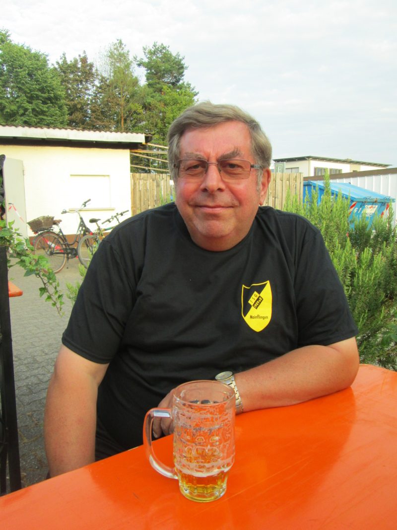 Hauptvortstandsvorsitzender Michael Seifert im schwarzen Shirt mit TSG Wappen, sitzend an einem Biertisch beim Mainpokal 2019