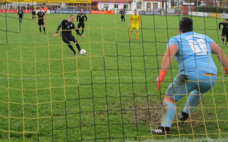 Elfemter für die TSG. Aufnahme direkt hinter dem Tor, der Schütze trifft gerade den Ball, der Torwart setzt zum Sprung in seine rechte Ecke an