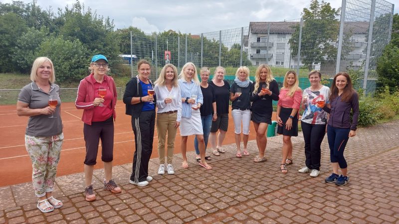 Gruppenfoto. 12 Frauen auf dem Tennisplatz weitestgehend nicht in Sportkleidung. 2/3 hält ein Weinglas in der Hand.
Anlass: Frauen Brunch 2021