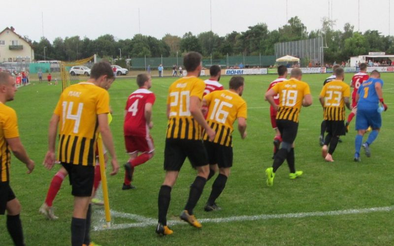 Die Teams aus Mainflingen (gelb-schwarz-gestreifte Trikots) und Hainstadt (rote Trikots) beim Einlaufen von einer Eckfahne aus zum Halbfinale des Mainpokals 2019