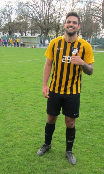 Enrico Di Natale, Spieler der TSG in gelb-schwarz gestreiftem Trikot. Steht auf dem Fußballplatz und hebt die linke Hand mit Daumen nach oben.