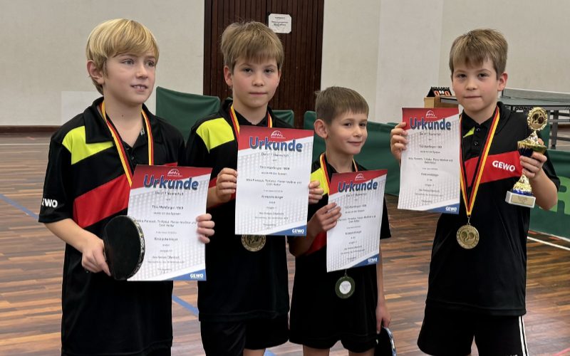 Gruppenfoto: Tischtennis J11 Team (vier Jungen) in Sportkleidung, Urkunden in der Hand und einem Pokal